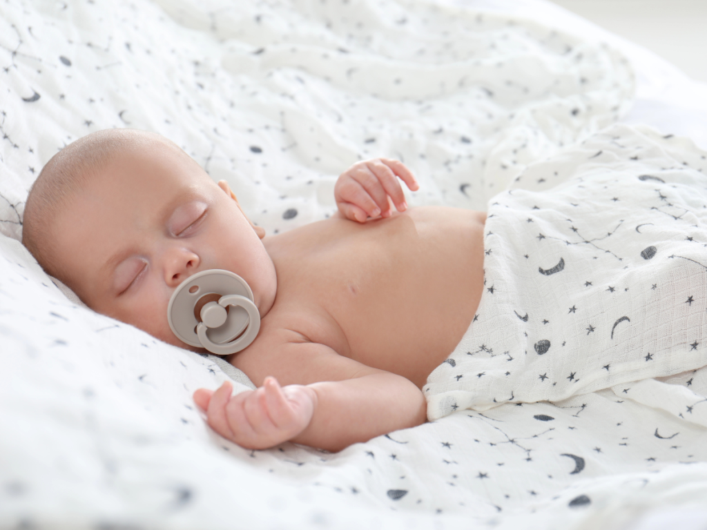 Newborn baby sleeping with a soft wrap as part of baby sleep essentials