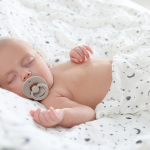 Newborn baby sleeping with a soft wrap as part of baby sleep essentials